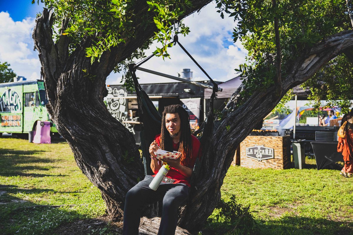 A festival-goer relaxes in a hammock swing between food trucks