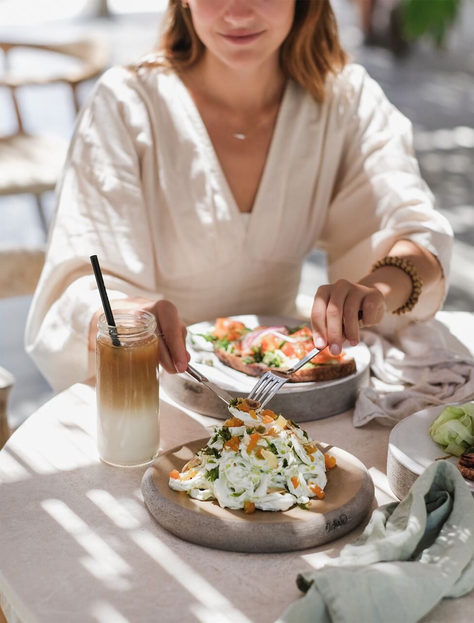 Woman enjoying fresh Tulum brunch with iced coffee