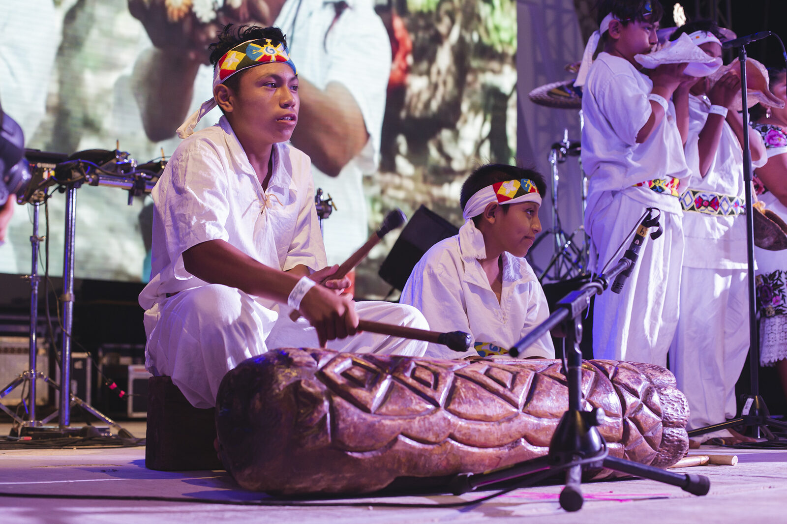 Young Maya musicians performing with traditional drums and conch shell