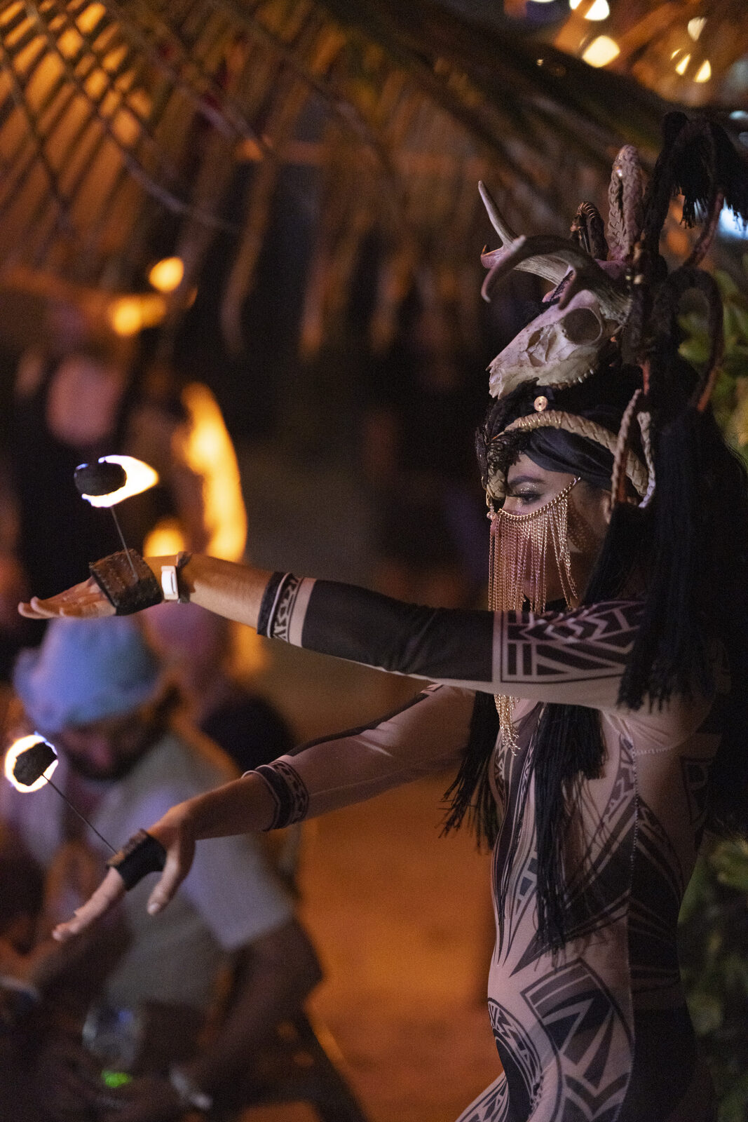 Fire dancer with horned headdress performing at Tulum night event
